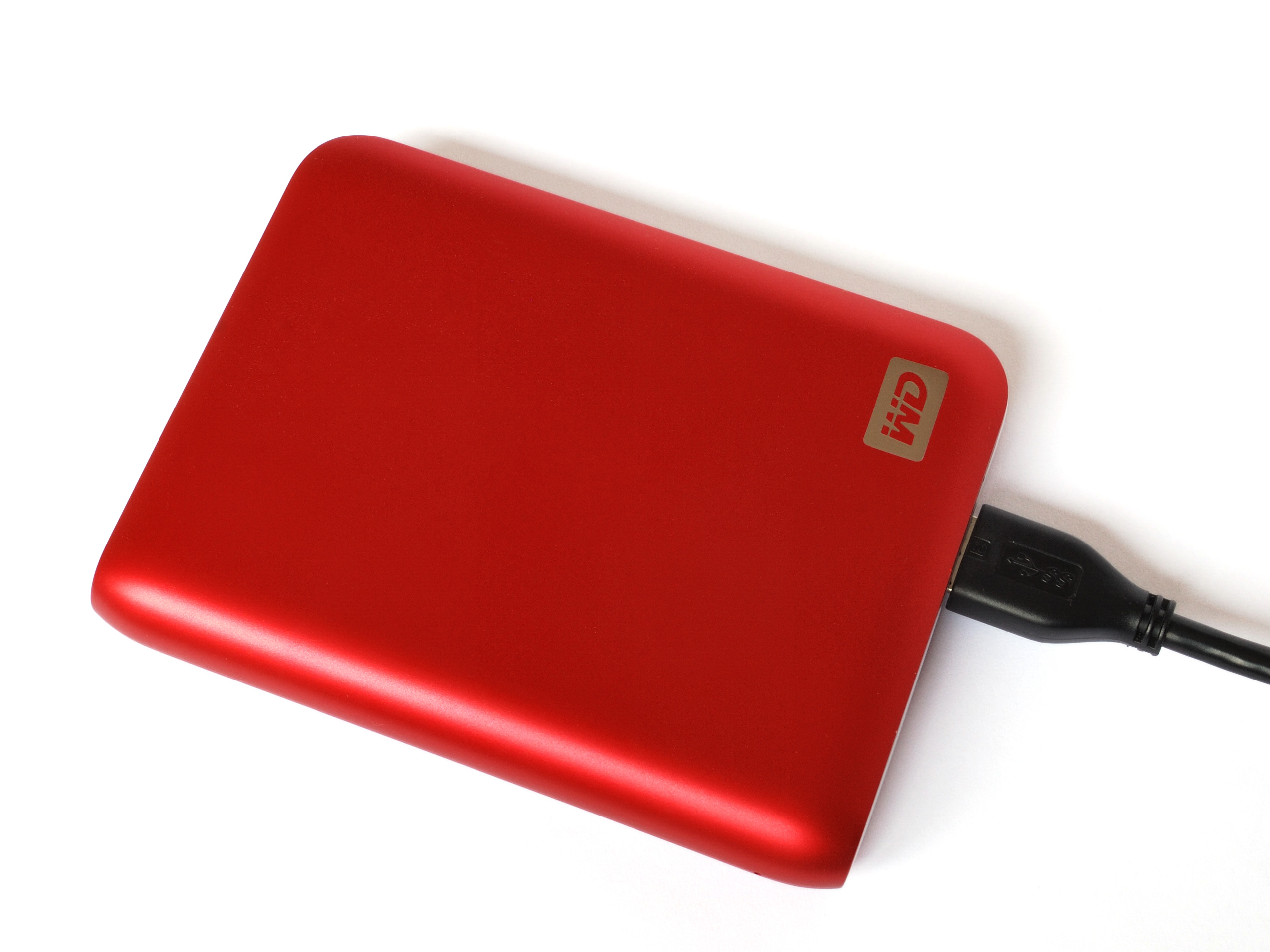 A red, rectangular External Hard Drive connected to a black cable.