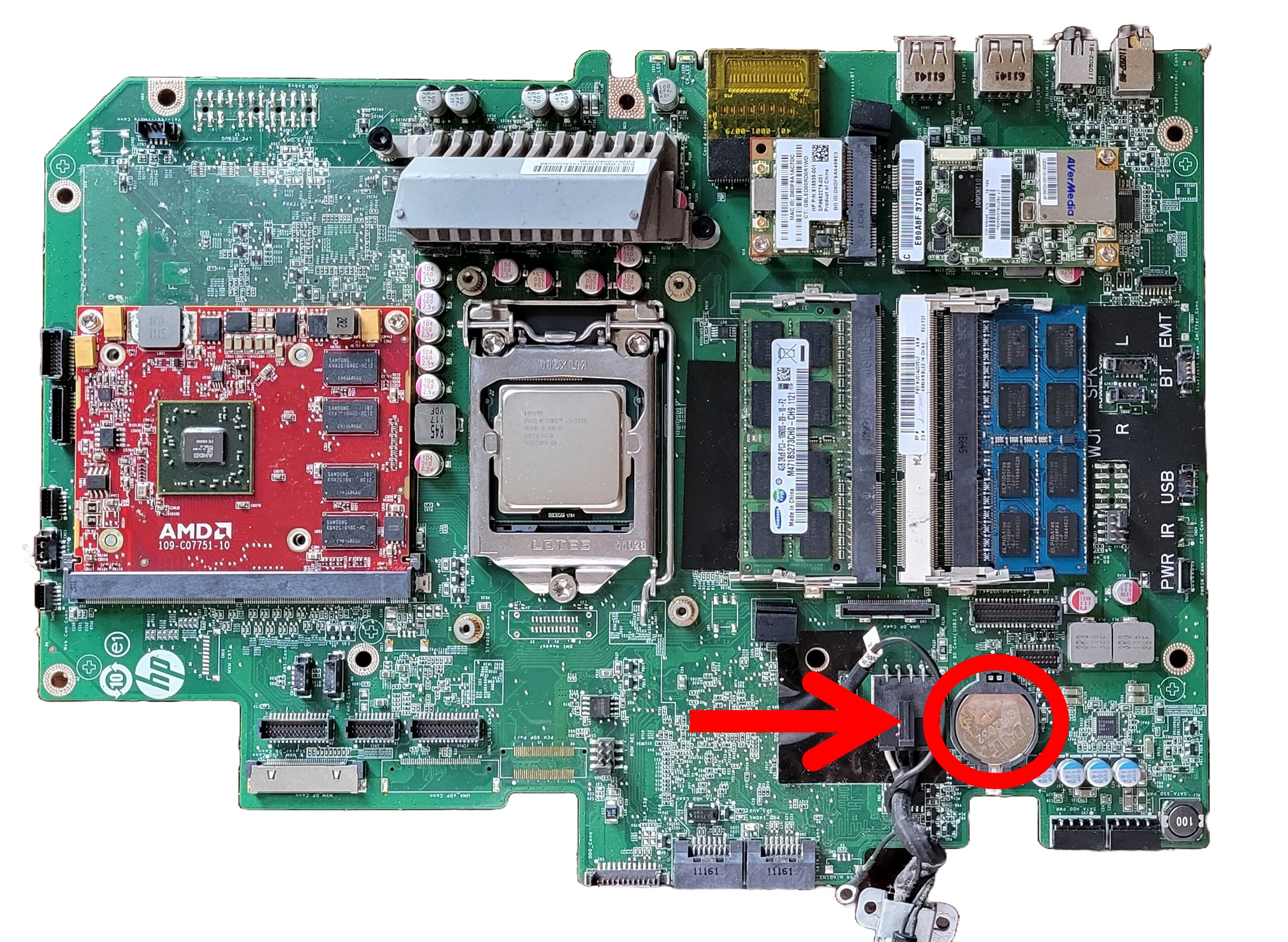 A small, circular, metalic battery installed at the bottom (south) portion of the motherboard (encircled in red.)