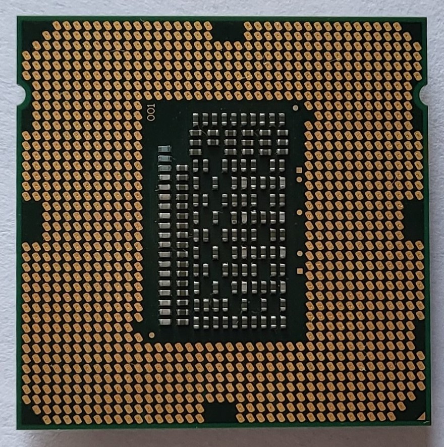 A bottom (inner) view of the square, nearly-flat silver-colored metal cpu chip: the small copper touchpoints all across this surface are visible.