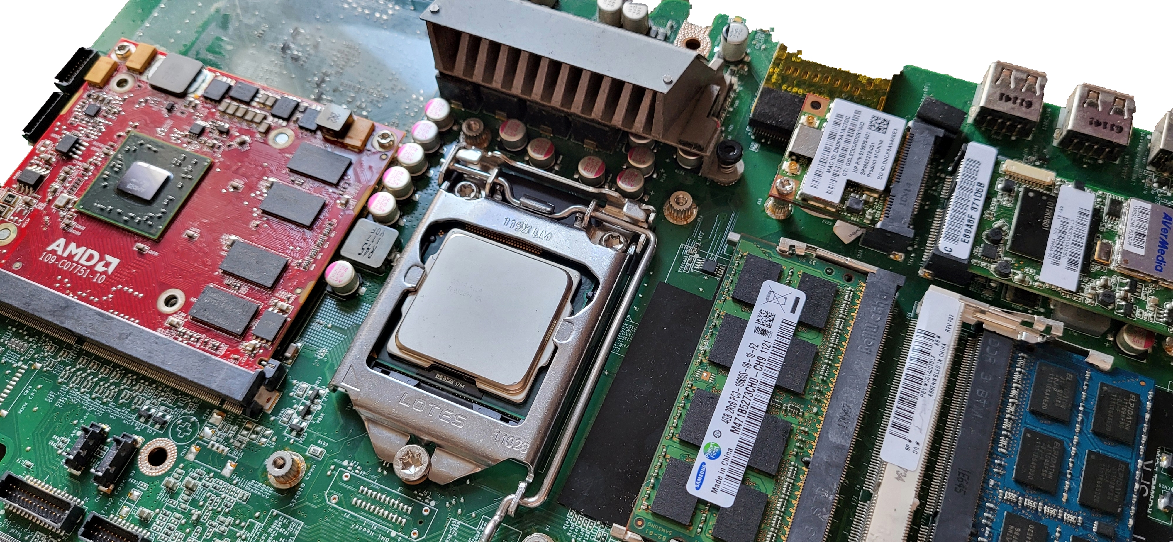 An oblique-angle view of a desktop computer's green-colored motherboard, featuring (right to left) two memory chips, a cpu chip, and a graphics card.